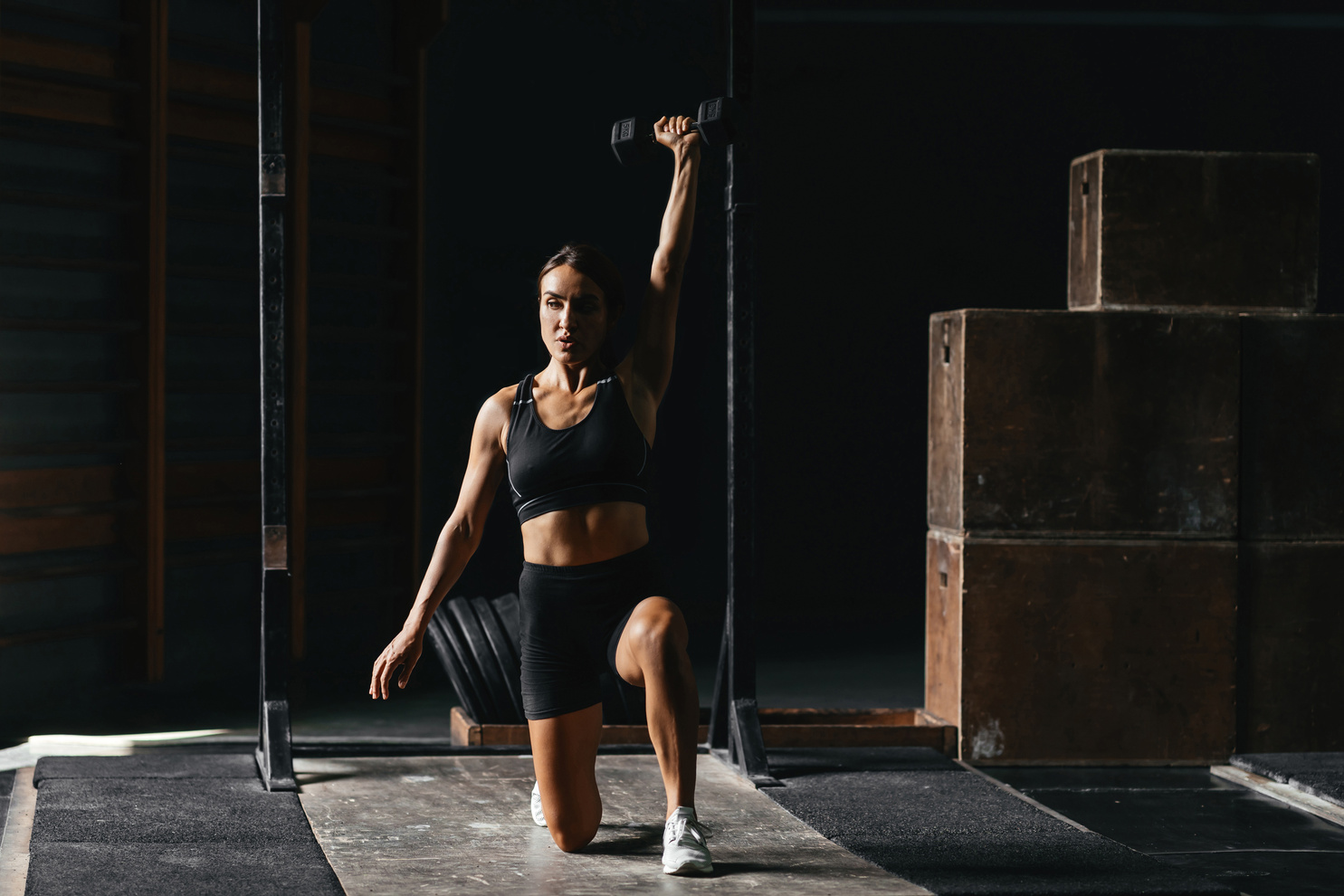 Fit young woman at a crossfit style on dark gray background.